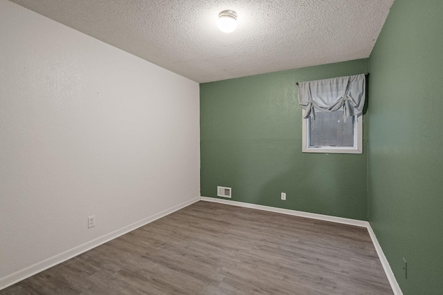 2101 6th Ave NE, Austin, MN 55912 - spare room featuring a textured ceiling, wood finished floors, and baseboards