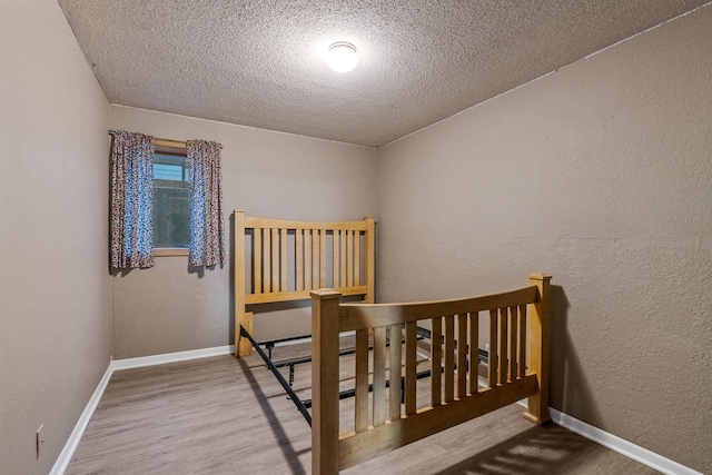 2101 6th Ave NE, Austin, MN 55912 - bedroom featuring a textured ceiling, wood finished floors, a textured wall, and baseboards