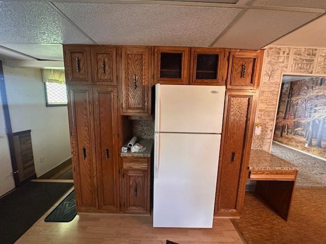 21 Glen Cir, Babbitt, MN 55706 - kitchen featuring freestanding refrigerator, brown cabinetry, light wood finished floors, and glass insert cabinets
