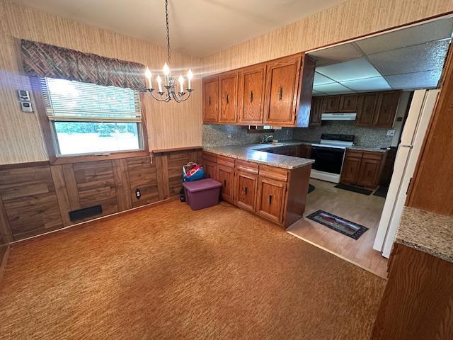 21 Glen Cir, Babbitt, MN 55706 - kitchen with white range with electric stovetop, a sink, light colored carpet, a chandelier, and brown cabinets