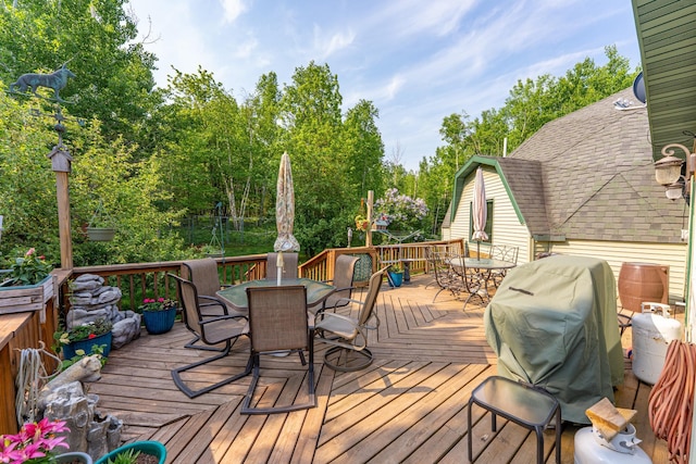 3382 Breezy Point Rd, Greenwood Twp, MN 55790 - deck featuring outdoor dining area, grilling area, and view of scattered trees