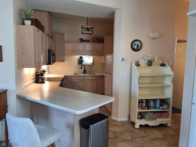 3307 38th St S, Moorhead, MN 56560 - kitchen featuring black microwave, a sink, light countertops, a breakfast bar, and freestanding refrigerator