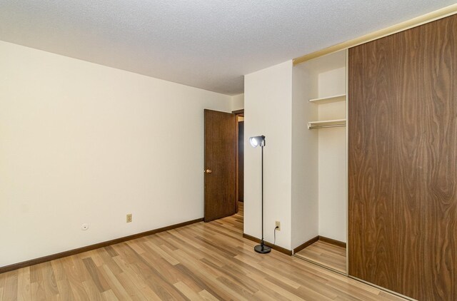 7880 Rimbley Rd, Woodbury, MN 55125 - unfurnished bedroom featuring light wood-style flooring, a closet, and a textured ceiling