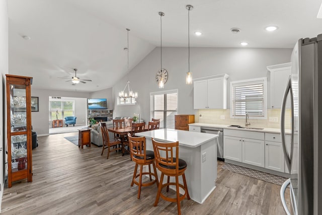 11164 184th Cir NW, Elk River, MN 55330 - kitchen featuring stainless steel appliances, a ceiling fan, a kitchen island, a fireplace, and light wood-style flooring
