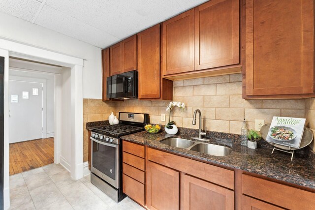786 Iglehart Ave, Saint Paul, MN 55104 - kitchen with black microwave, stainless steel range with gas stovetop, dark stone counters, decorative backsplash, and brown cabinets