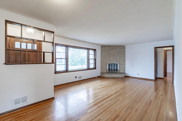 7533 16th Ave S, Richfield, MN 55423 - unfurnished living room featuring wood finished floors, baseboards, a fireplace, and a textured ceiling