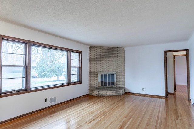 7533 16th Ave S, Richfield, MN 55423 - unfurnished living room with light wood-type flooring, baseboards, a textured ceiling, and a fireplace
