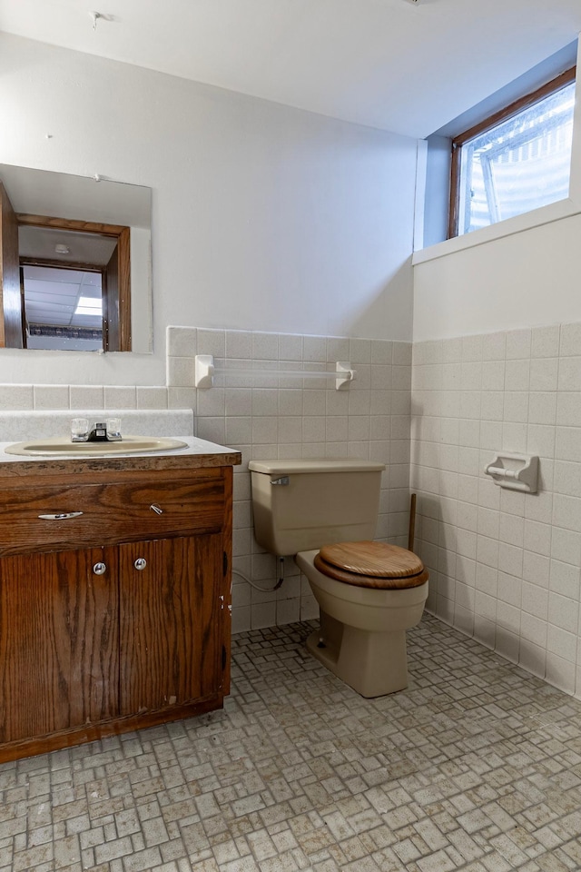 7533 16th Ave S, Richfield, MN 55423 - half bathroom featuring tile walls, toilet, vanity, wainscoting, and brick patterned flooring
