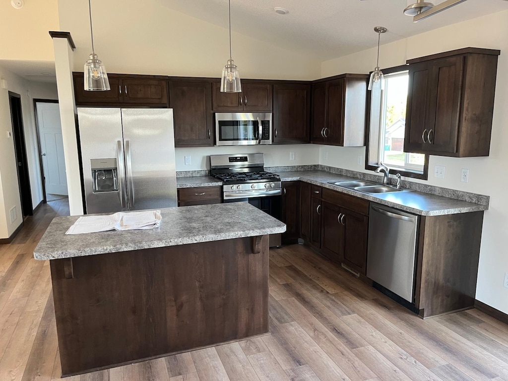 704 3rd Ave SE, Cold Spring, MN 56320 - kitchen featuring appliances with stainless steel finishes, a sink, dark brown cabinetry, vaulted ceiling, and a center island