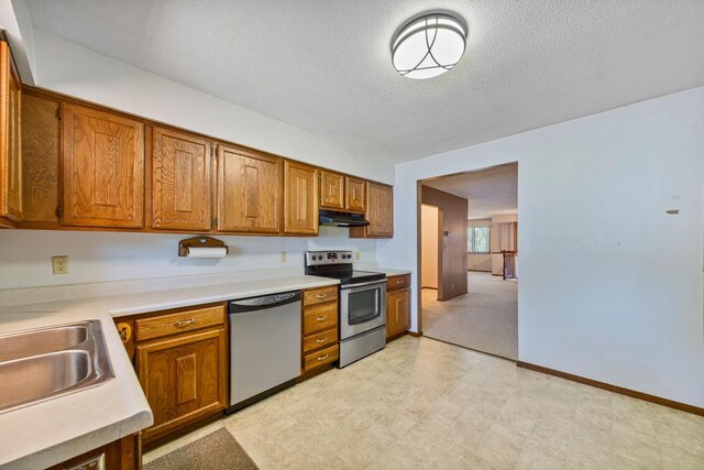 635 5th St, Windom, MN 56101 - kitchen featuring stainless steel appliances, under cabinet range hood, a textured ceiling, brown cabinets, and light countertops