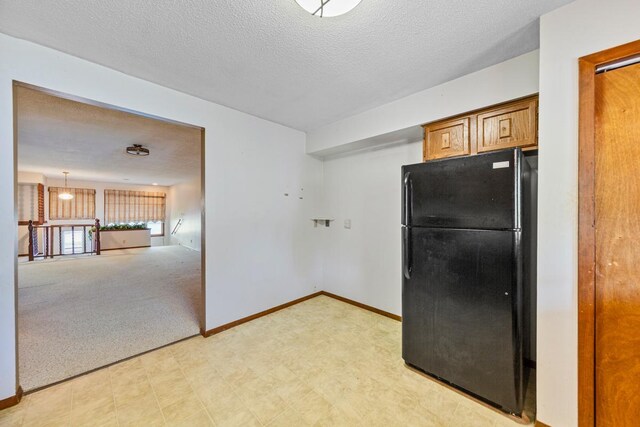 635 5th St, Windom, MN 56101 - kitchen featuring freestanding refrigerator, brown cabinets, a textured ceiling, and light flooring