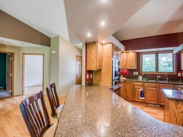 22152 Polaris Rd NW, Puposky, MN 56667 - kitchen with oven, recessed lighting, dark stone counters, light wood-type flooring, and brown cabinetry