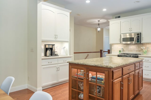 3543 Eben Way, Stillwater, MN 55082 - kitchen featuring stainless steel microwave, backsplash, light wood-type flooring, white cabinets, and recessed lighting