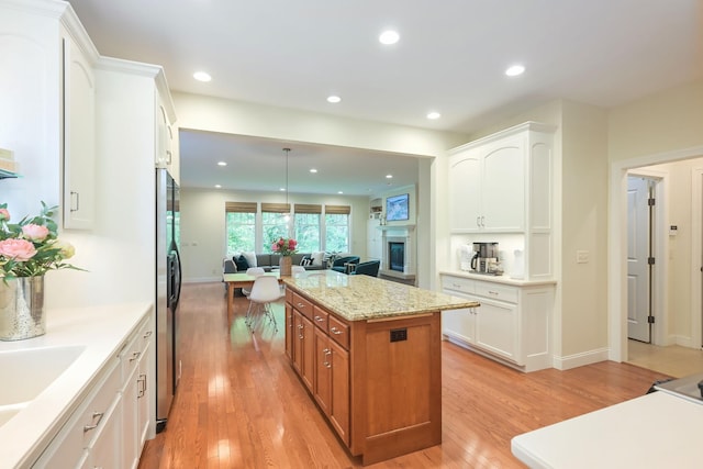 3543 Eben Way, Stillwater, MN 55082 - kitchen with open floor plan, a kitchen island, light wood-style flooring, brown cabinetry, and a fireplace