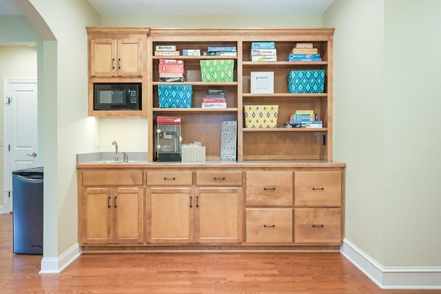3543 Eben Way, Stillwater, MN 55082 - indoor wet bar with black microwave, light wood finished floors, arched walkways, and baseboards
