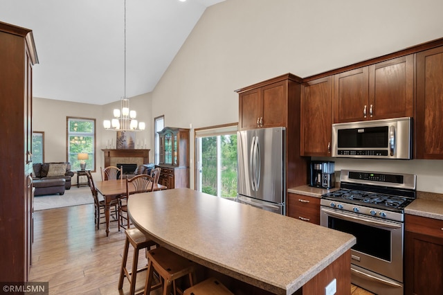 5261 Fenson Ct N, Hugo, MN 55038 - kitchen featuring stainless steel appliances, high vaulted ceiling, light wood finished floors, a chandelier, and open floor plan