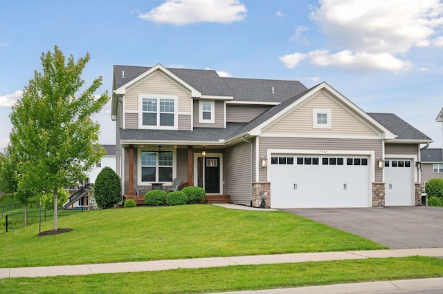 17552 57th St NE, Otsego, MN 55374 - view of front of home with covered porch, asphalt driveway, an attached garage, roof with shingles, and stone siding