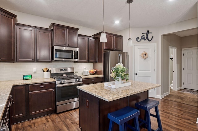 17552 57th St NE, Otsego, MN 55374 - kitchen featuring appliances with stainless steel finishes, a kitchen bar, tasteful backsplash, dark brown cabinets, and recessed lighting