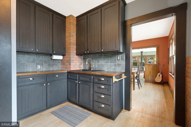 5116 28th Ave S, Minneapolis, MN 55417 - kitchen featuring a sink, light wood finished floors, backsplash, dark countertops, and dark brown cabinets