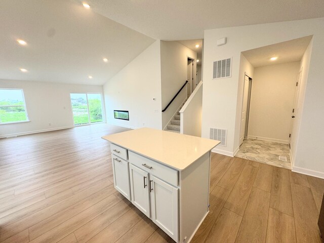 7031 Lannon Ave NE, Otsego, MN 55301 - kitchen with light wood-type flooring, a kitchen island, white cabinets, light countertops, and recessed lighting