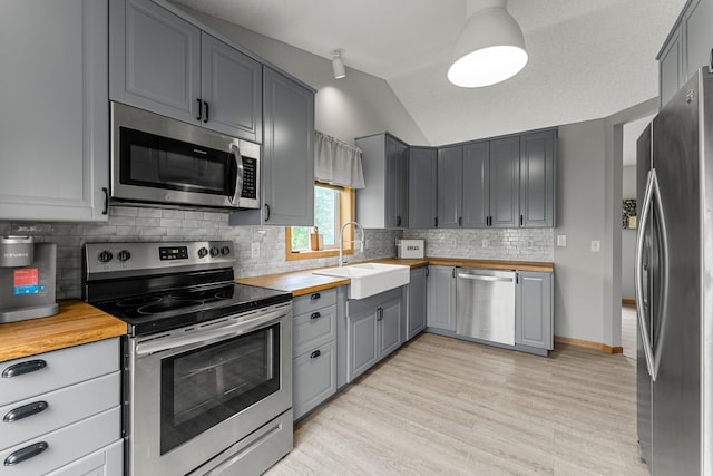 920 Lincoln Ct S, Cambridge, MN 55008 - kitchen with appliances with stainless steel finishes, gray cabinetry, butcher block counters, vaulted ceiling, and light wood-style floors