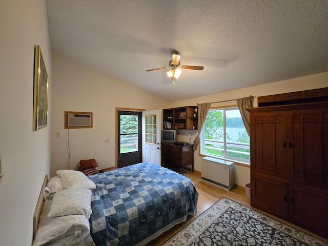 35163 Rose Lake Dr, Frazee, MN 56544 - bedroom with a wall unit AC, multiple windows, light wood-type flooring, vaulted ceiling, and a textured ceiling