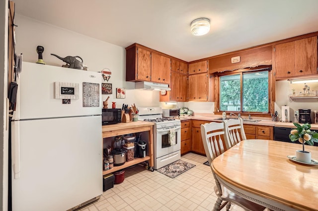 2226 S Ave E, North Saint Paul, MN 55109 - kitchen featuring white appliances, under cabinet range hood, brown cabinetry, and brick patterned floors