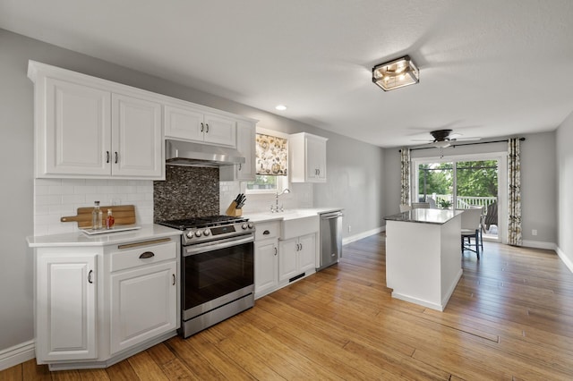 12864 Fondant Trl N, Hugo, MN 55038 - kitchen featuring appliances with stainless steel finishes, extractor fan, decorative backsplash, white cabinets, and recessed lighting