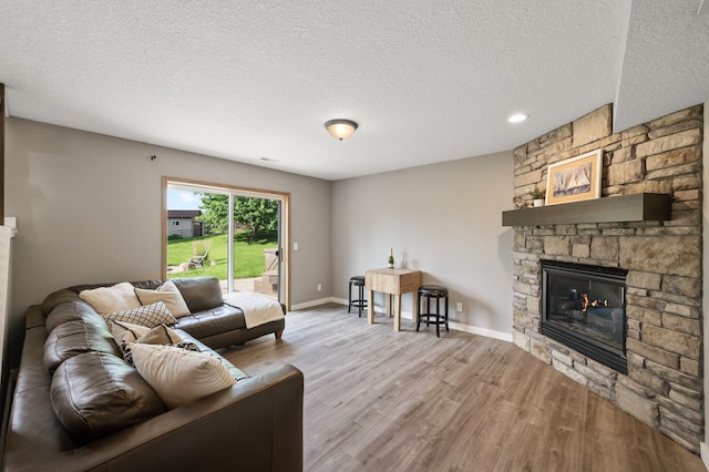 12864 Fondant Trl N, Hugo, MN 55038 - living area with a stone fireplace, wood finished floors, and a textured ceiling