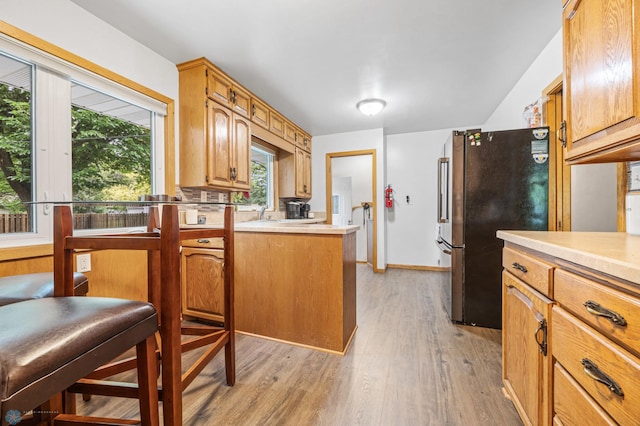 1917 7th St S, Moorhead, MN 56560 - kitchen featuring freestanding refrigerator, light wood-style flooring, light countertops, and a peninsula