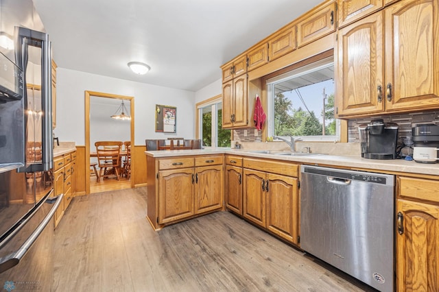 1917 7th St S, Moorhead, MN 56560 - kitchen with stainless steel appliances, a peninsula, light wood finished floors, light countertops, and decorative backsplash