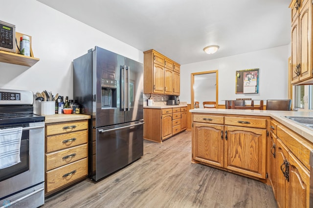 1917 7th St S, Moorhead, MN 56560 - kitchen featuring appliances with stainless steel finishes, light wood-type flooring, light countertops, a peninsula, and brown cabinetry