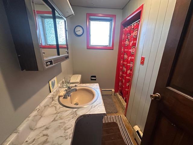 38 Locust Dr, Babbitt, MN 55706 - bathroom featuring a baseboard radiator, vanity, a baseboard heating unit, toilet, and a shower with shower curtain