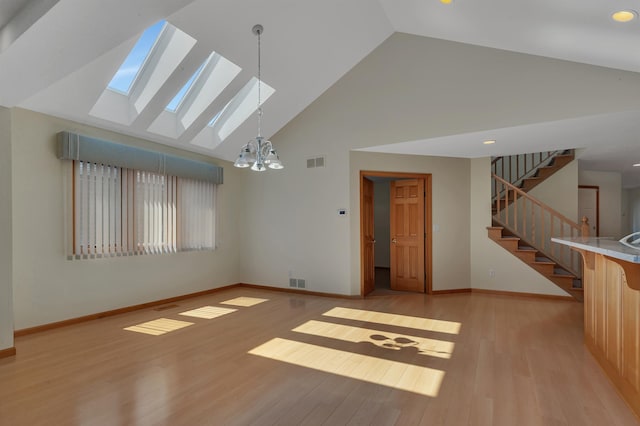 332 Waite Ave S, Saint Cloud, MN 56301 - unfurnished living room with high vaulted ceiling, a skylight, a chandelier, stairway, and light wood-style flooring