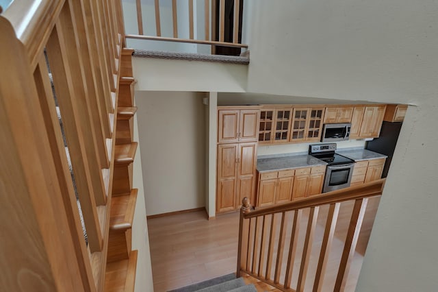 332 Waite Ave S, Saint Cloud, MN 56301 - kitchen featuring stainless steel appliances, glass insert cabinets, light brown cabinets, light wood-style flooring, and a high ceiling