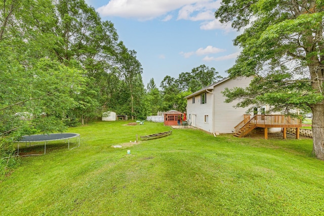 3220 Vine St, Cambridge, MN 55008 - view of green lawn with a trampoline, a storage shed, a deck, and stairs