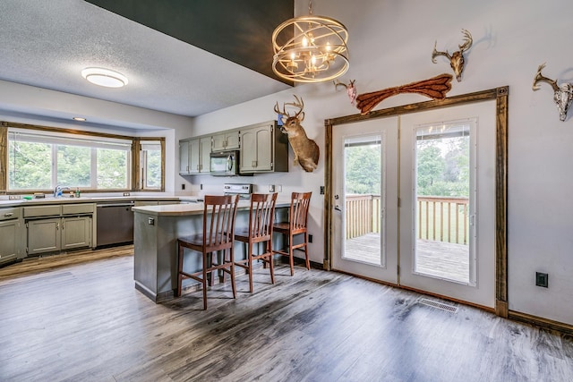 3220 Vine St, Cambridge, MN 55008 - kitchen featuring dishwasher, a peninsula, plenty of natural light, a chandelier, and a textured ceiling
