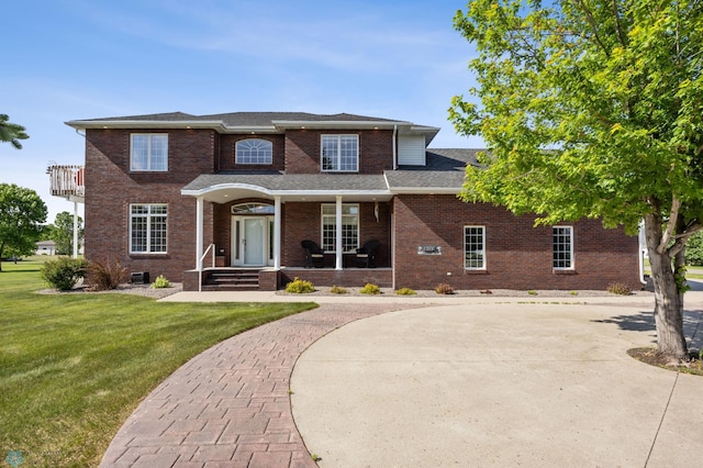 215 51st Ave E, West Fargo, ND 58078 - traditional-style house featuring brick siding, a front yard, curved driveway, covered porch, and a shingled roof