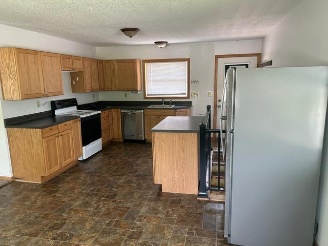 903 3rd Ave, Grand Rapids, MN 55744 - kitchen with stainless steel appliances, a sink, dark countertops, dark stone finish floors, and a textured ceiling