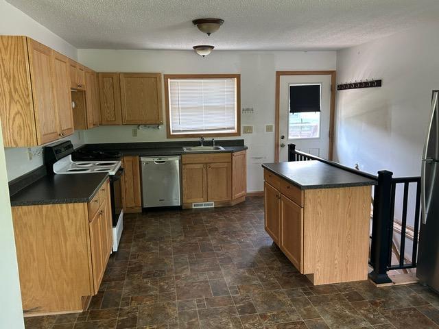 903 3rd Ave, Grand Rapids, MN 55744 - kitchen featuring stainless steel appliances, a sink, dark countertops, dark stone finish flooring, and a textured ceiling