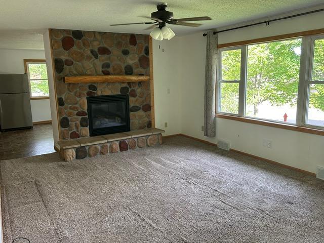 903 3rd Ave, Grand Rapids, MN 55744 - unfurnished living room with ceiling fan, baseboards, a fireplace, carpet floors, and a textured ceiling