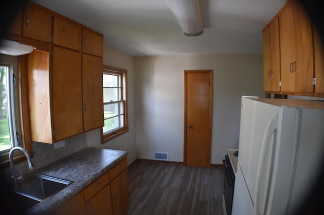 13 S St, Morris, MN 56267 - kitchen with freestanding refrigerator, dark wood-type flooring, brown cabinetry, decorative backsplash, and dark countertops