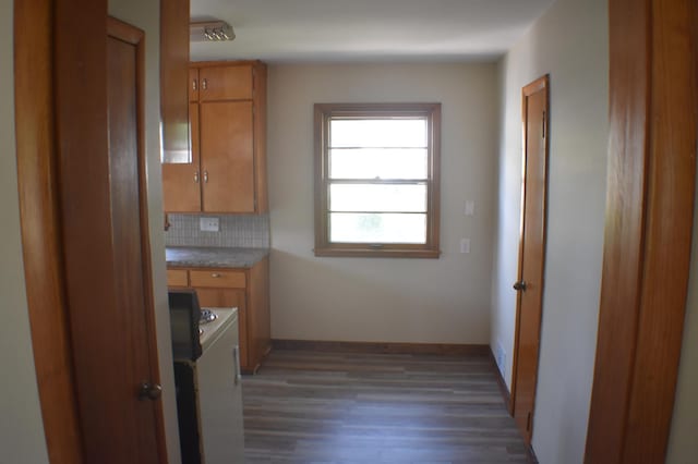 13 S St, Morris, MN 56267 - kitchen featuring washer and clothes dryer, wood finished floors, light countertops, brown cabinetry, and decorative backsplash