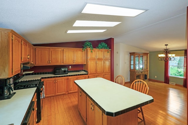 10196 48th St, Clear Lake, MN 55319 - kitchen featuring black appliances, lofted ceiling, a breakfast bar area, light wood-type flooring, and under cabinet range hood