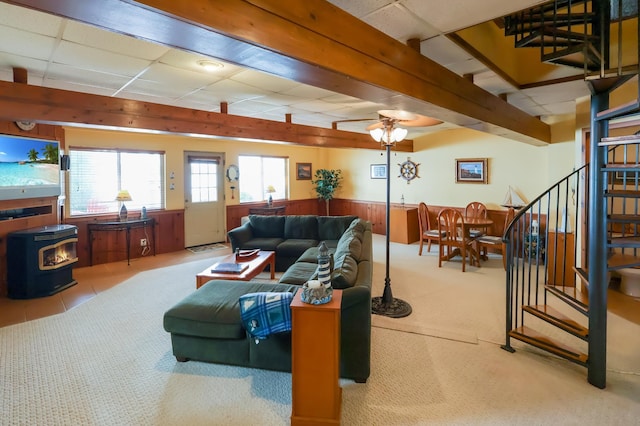 10196 48th St, Clear Lake, MN 55319 - carpeted living area with a wood stove, stairs, wainscoting, wood walls, and a ceiling fan