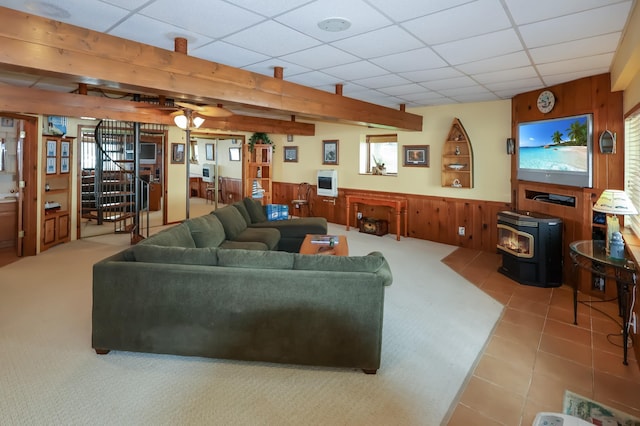 10196 48th St, Clear Lake, MN 55319 - tiled living room featuring a wood stove, a wainscoted wall, a paneled ceiling, wood walls, and carpet floors