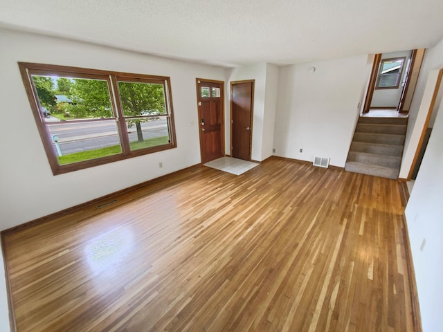8337 80th St S, Cottage Grove, MN 55016 - unfurnished living room featuring light wood-style flooring, stairway, baseboards, and a textured ceiling