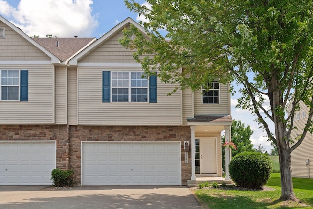 2936 18th Ave E, Shakopee, MN 55379 - townhome / multi-family property featuring stone siding, driveway, an attached garage, and roof with shingles