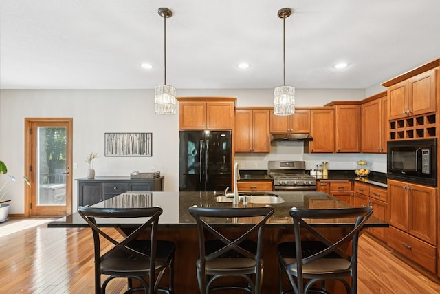 1020 Bliss Ln, Bloomington, MN 55431 - kitchen with black appliances, under cabinet range hood, light wood-style floors, brown cabinetry, and recessed lighting