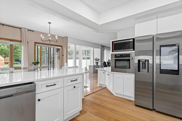 3817 Dunbar Ct N, Brooklyn Park, MN 55443 - kitchen featuring stainless steel appliances, a chandelier, white cabinets, light wood finished floors, and decorative light fixtures